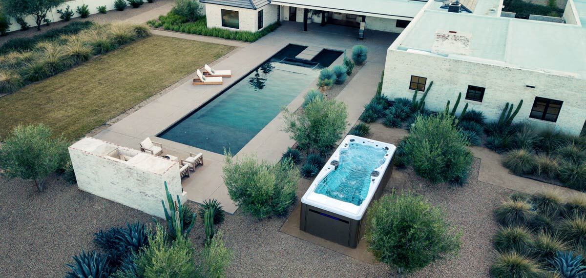 Drone view of a backyard witha swim spa and a pool.